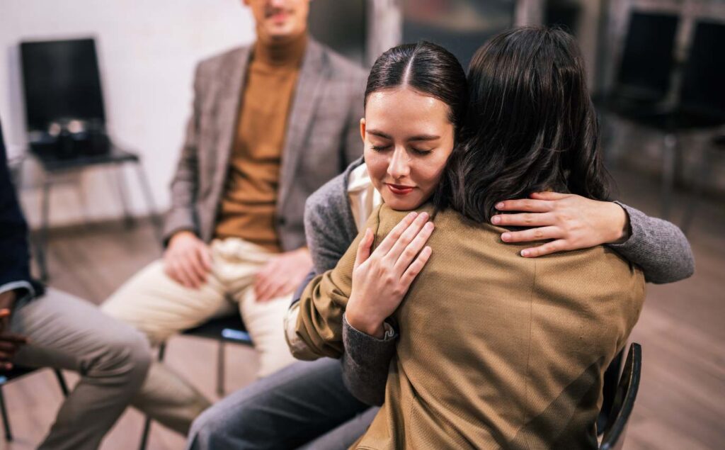 People hugging during a group therapy session at a Chula Vista rehab center.