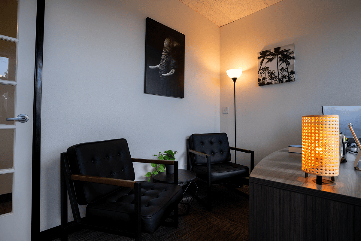 Comfortable counseling office with chairs, lamp, and artwork for mental health support.