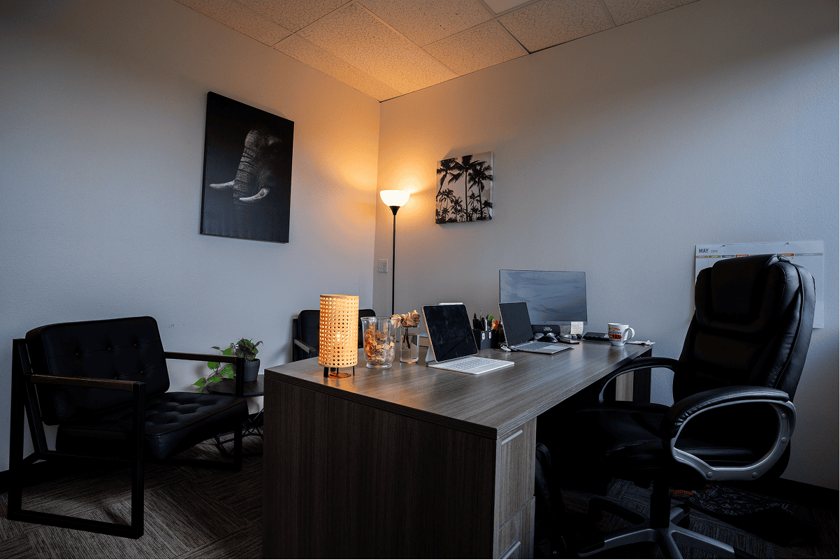 Comfortable therapy office with desk, chairs, and calming decor.