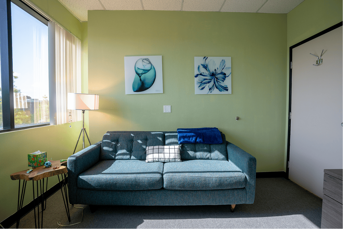 Therapy room with sofa, artwork, and natural light for mental health treatment.