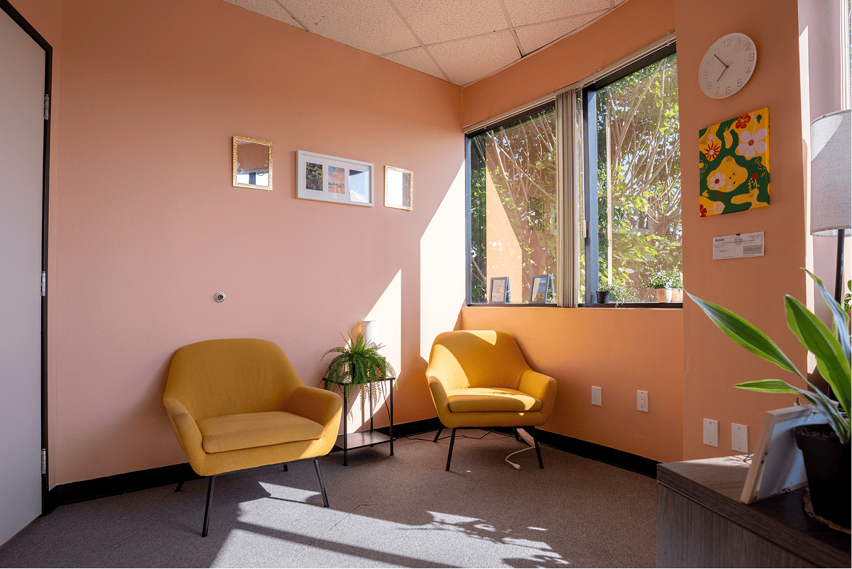 Bright therapy room with yellow chairs and large windows for natural light.
