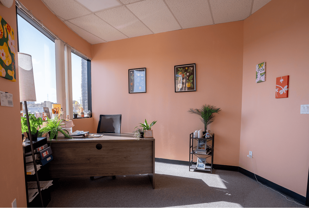 Comfortable therapy office with desk, plants, and artwork for mental health support.