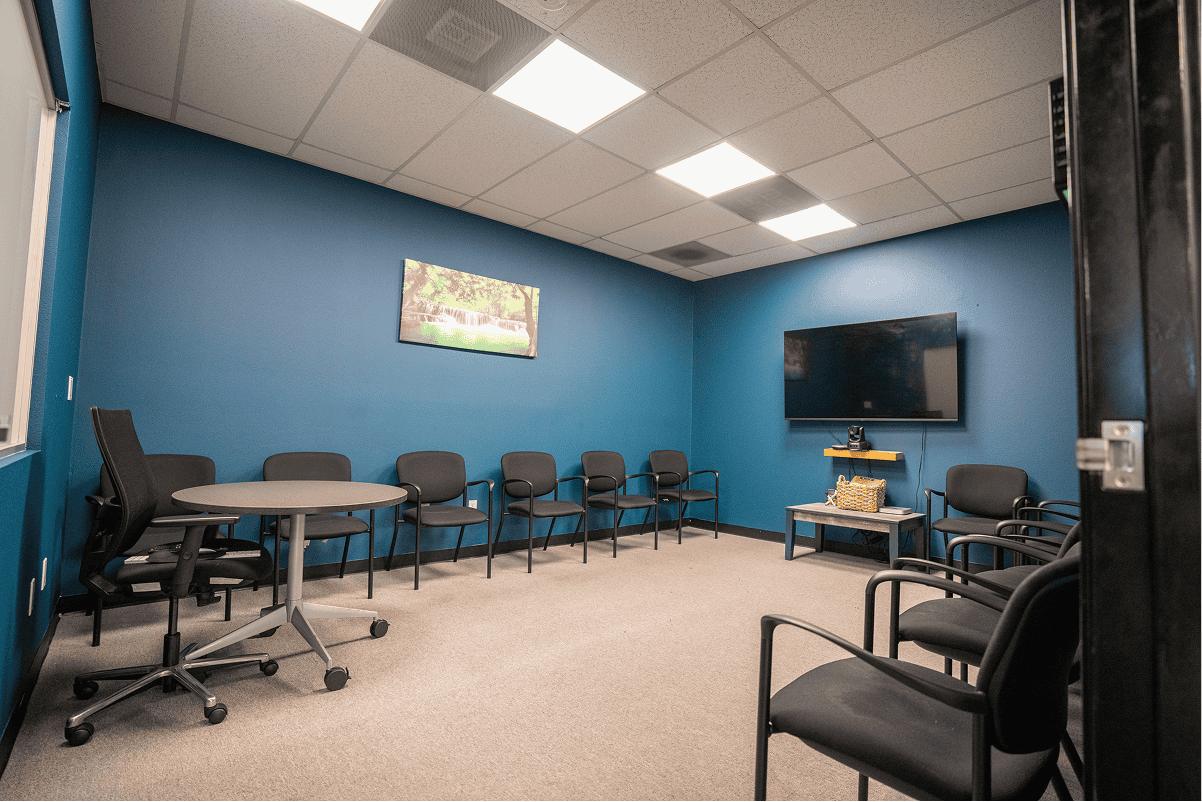 Counseling room with chairs, TV, and blue walls at Assure Recovery.